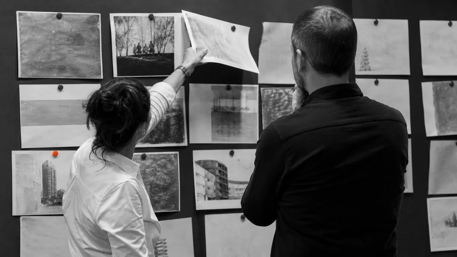 Deux professionnels retirant une page d'un mur de contenus, scène d'arbitrage éditorial