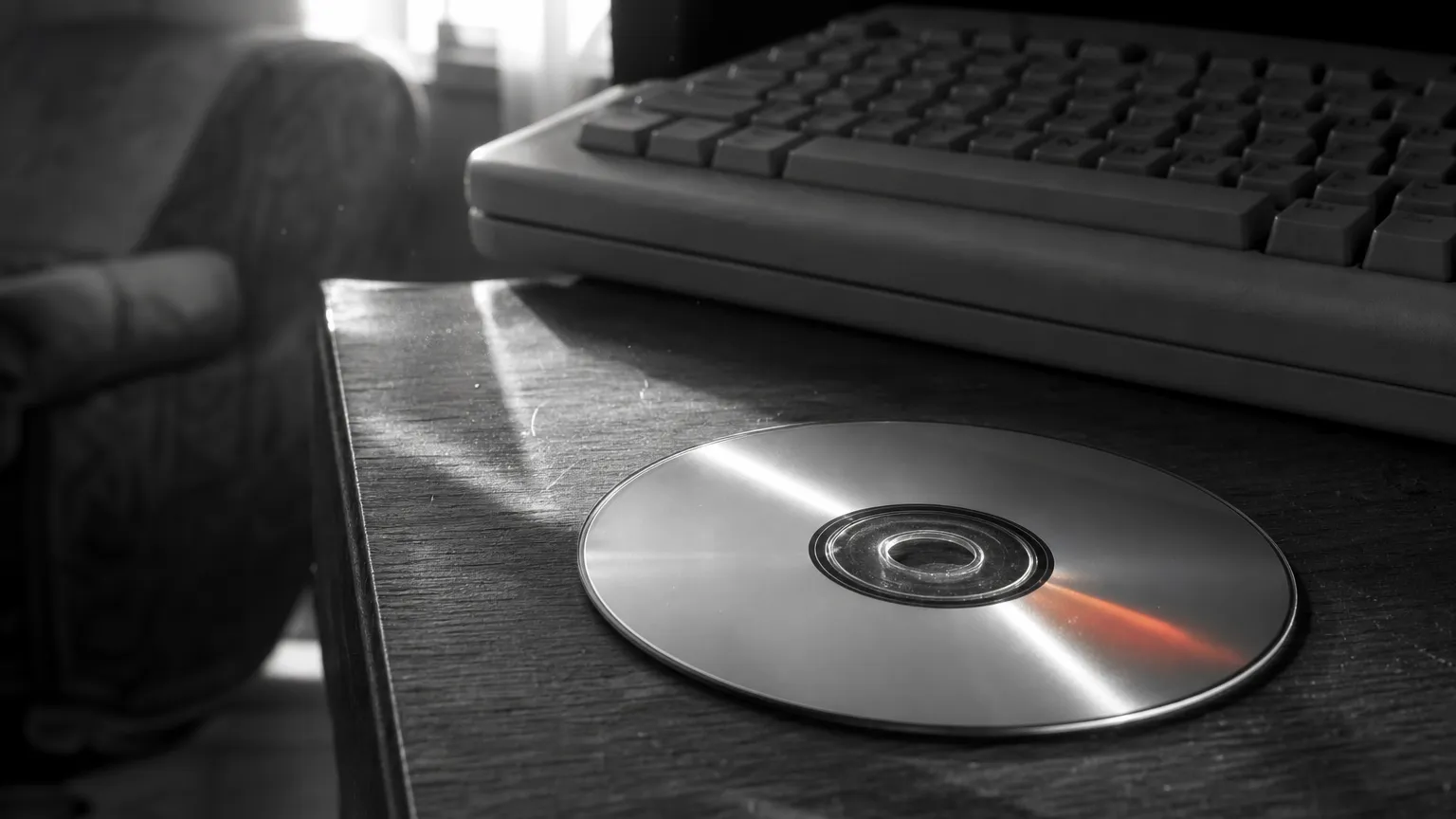 Un disque compact posé sur une table près d'un clavier d'ordinateur des années 1990